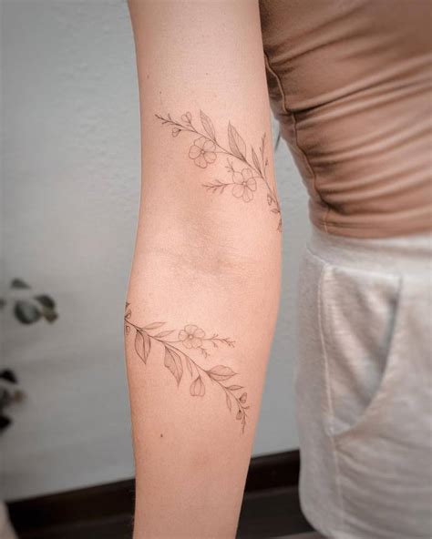 Fine line flower bracelet tattoo located on the arm.