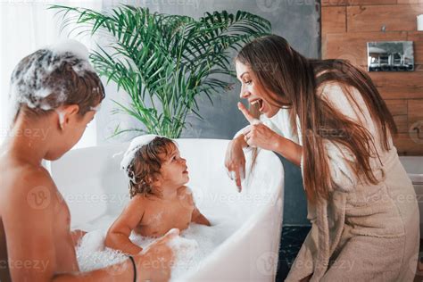 Having fun. Young mother helps her son and daughter. Two kids washing