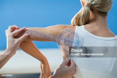 terapis pria mengukur bahu pasien wanita  goniometer foto stok