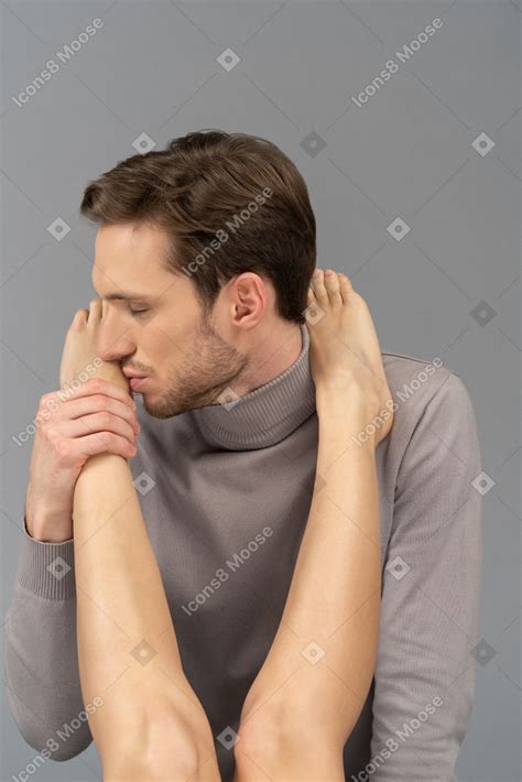 A pleased young man kissing a female`s foot Photo