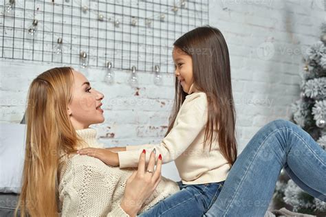 Beautiful young woman and her charming little daughter are hugging
