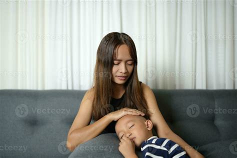 A son sleeps on his mother's lap inside the house. 32734005 Stock Photo