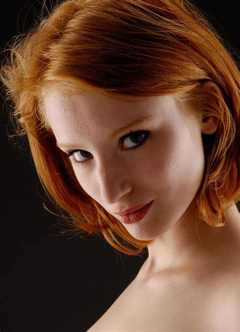 a woman with red hair and blue eyes is posing for the camera while