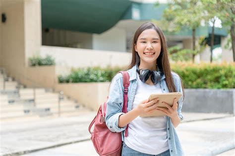 Beautiful student asian woman with backpack and books outdoor. Smile