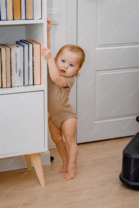 A toddler standing on his tip toes toe walking a baby learning to stand
