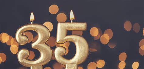 Gold number 35 celebration candle against blurred light background ...