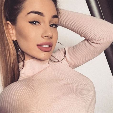 a woman with long hair wearing a pink sweater and hoop earrings is ...