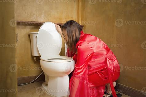 A woman in a red nightgown vomiting in the bathroom. 17696028 Stock