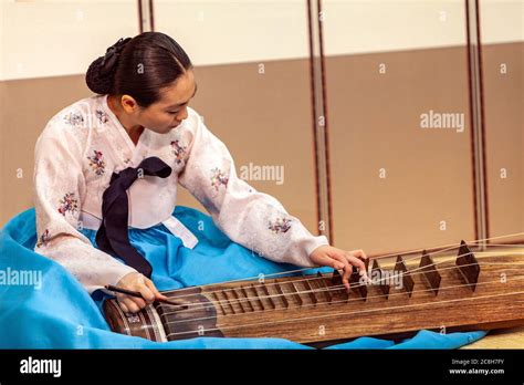 A Korean woman wearing a traditional Hanbok , playing the Geomungo at ...