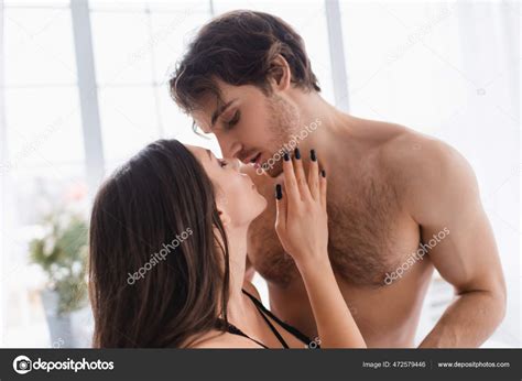 seductive woman bra kissing muscular man home stock photo