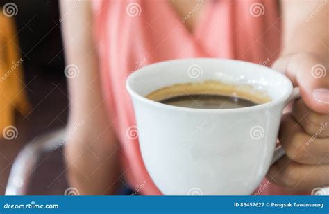 Рука женщины крупного плана держа чашку горячего кофе Americano ...