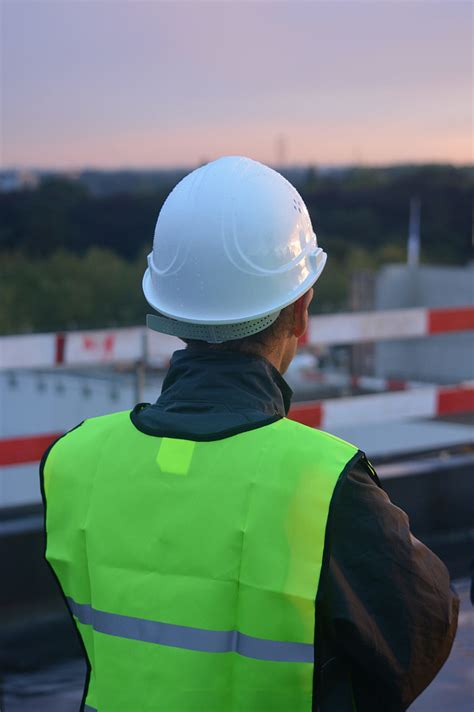 Royalty-Free photo: Man in green high-visibility vest with white hard ...