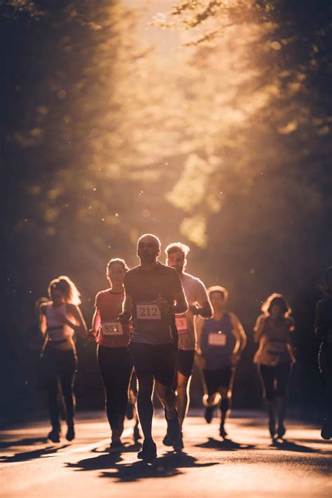 Group of determined athletes running marathon at sunset.