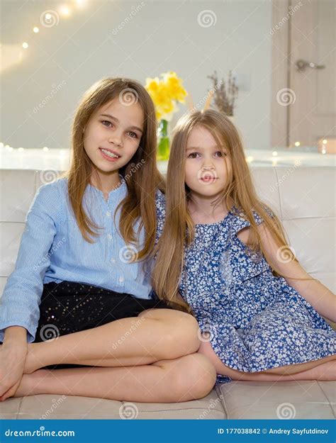 Two Sisters Sit on White Sofa at Home and Watch TV Stock Photo - Image