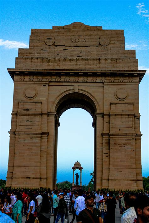 A crowd of people standing around a stone arch photo – Free Girl Image