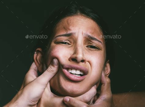 Shot of hands grabbing a young womans neck against a dark background ...