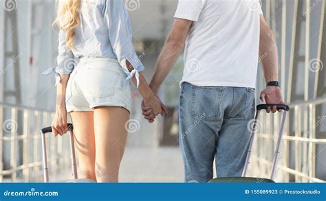 couple holding hands carrying luggage  airport stock image image