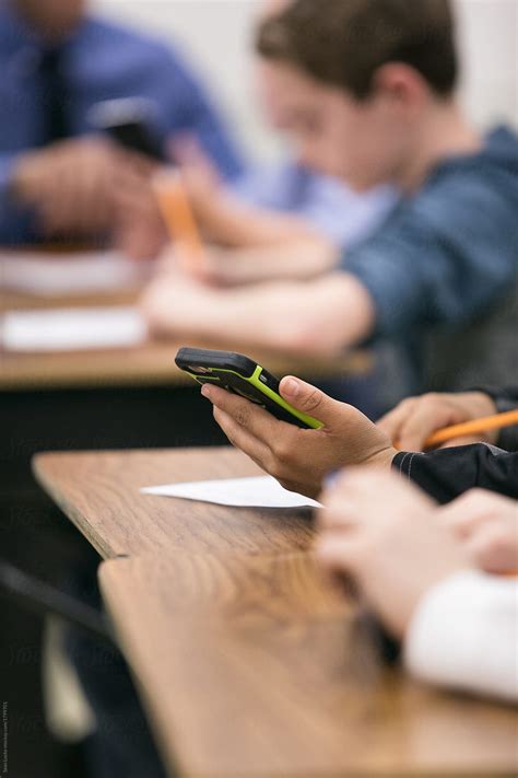 "Classroom: Student Uses Cell Phone While Doing Schoolwork" by Stocksy