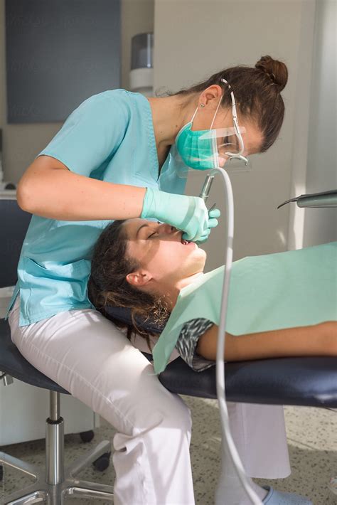 Orthodontist curing her patient using dental drill by RG&B Images