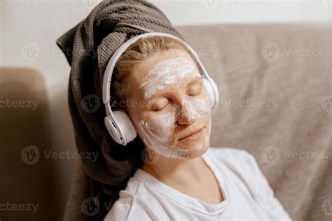 Young woman with casual clothes, towel on head and beauty mask on face
