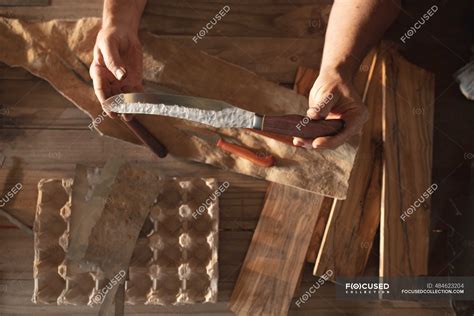 hands  caucasian male knife maker  workshop holding handmade knife