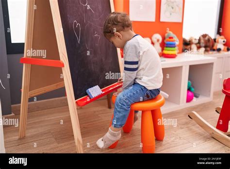 Adorable caucasian boy preschool student sitting on chair drawing on