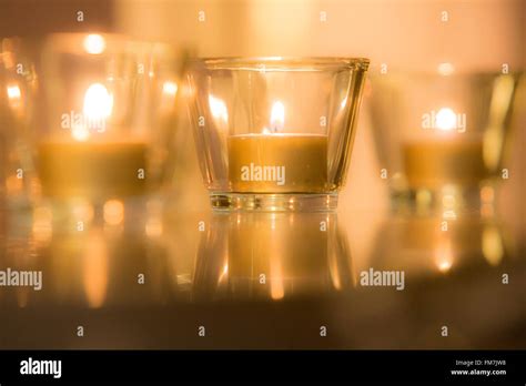 Tiny tea light candles glowing and flickering with warm light in glass ...