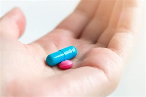 Premium Photo | Blue and pink pill capsule on the female palm on white background ...