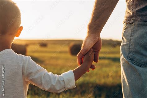 Foto Stock Father's and his son holding hands at sunset field. Dad ...