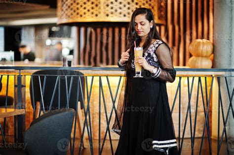 Pretty indian girl in black saree dress posed at restaurant with orange
