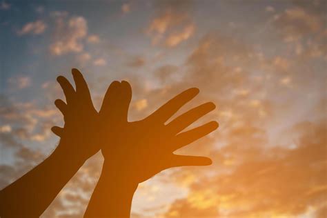 Silhouette with hands making bird shape on sunset sky for background ...