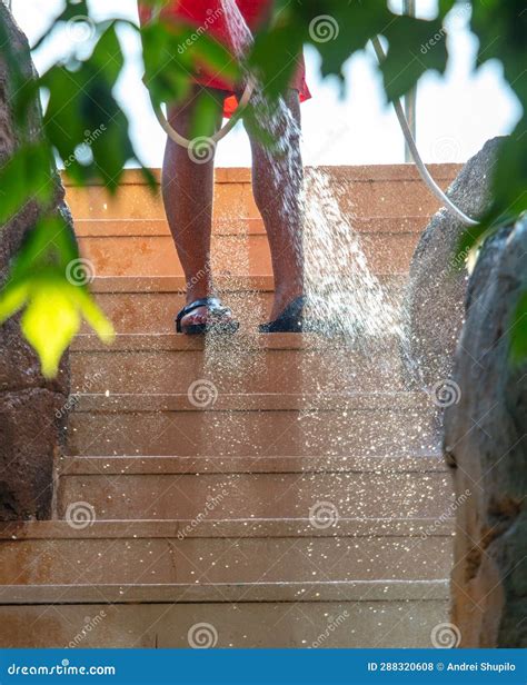 A Man Cleans the Stairs with Water from a Hose in the Park Stock Photo