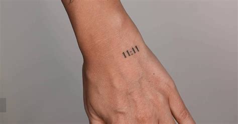 Angel number "11:11" tattoo located on the hand.