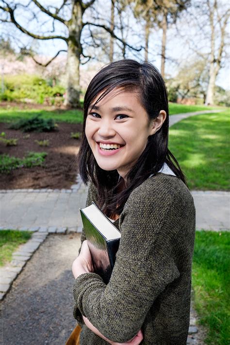 "Asian College Student Carrying A Book On Campus" by Stocksy