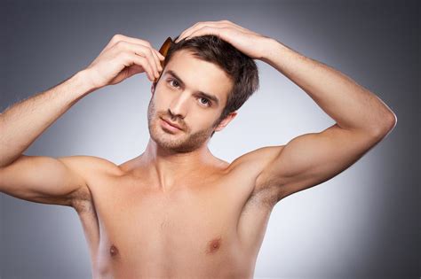 Making his hairstyle. Handsome young beard man looking at camera and