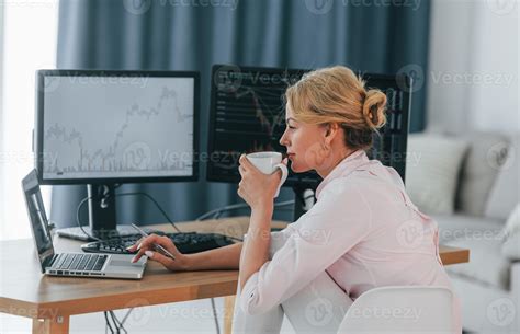 sentado con una taza de bebida en las manos y monitoreando el mercado
