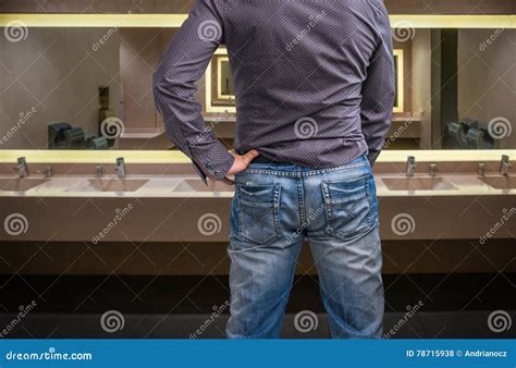 man adjusts  peeing   public toilet stock photo image