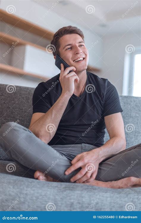 handsome guy talking   smartphone   living room stock photo