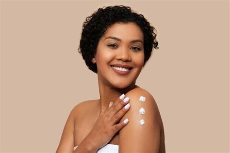 premium photo woman applying cream   arm beige background