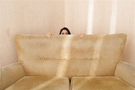 "Young Woman Hiding Behind A Retro Couch" by Stocksy Contributor "Ulas ...
