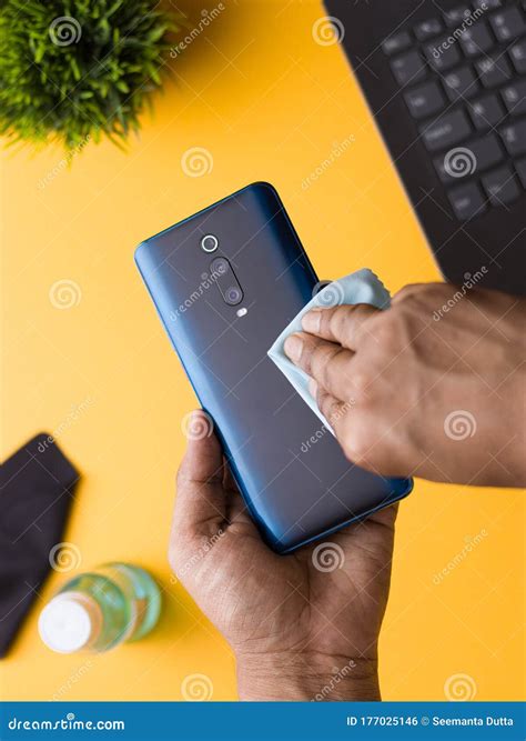 Cleaning Phone To Eliminate Germs Like COVID-19. Stock Photo - Image of