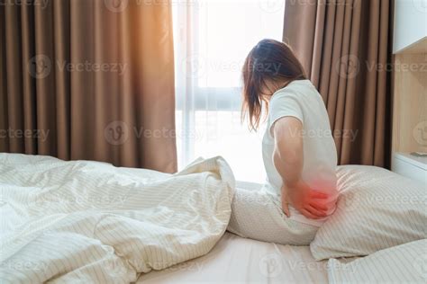 woman having back body ache during sitting on bed at home. adult female