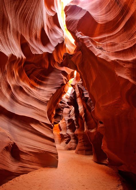 a narrow slot in the side of a canyon with light coming from it's windows