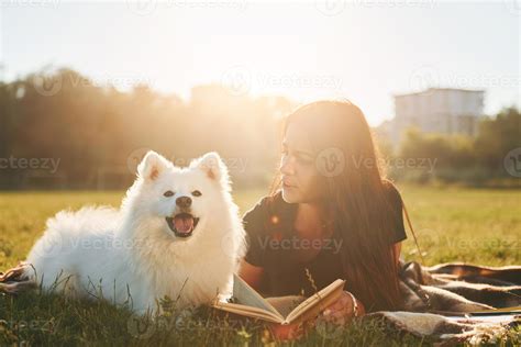Woman with her dog is having fun on the field at sunny daytime