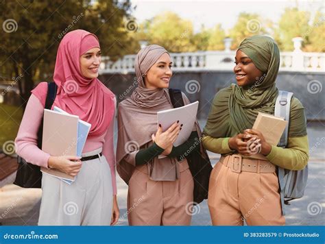 muslim female students  hijab holding books standing outdoors