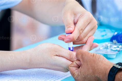 Doctor is drawing blood from fingertip to test patient's blood type