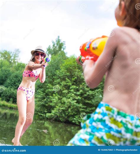 Young Girl Playing Squirt Guns with Her Brother on Pier during Summer