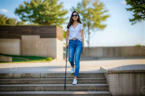 AI generated A blind Asian young woman wearing sunglasses walks down
