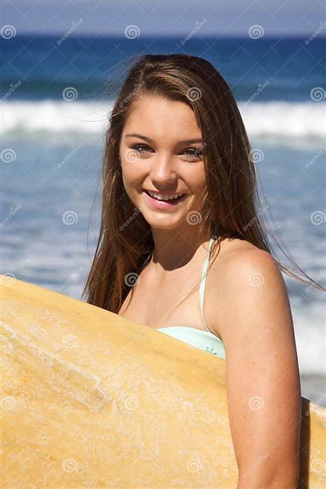 beautiful teenage girl holding  surfboard   beach smiling stock
