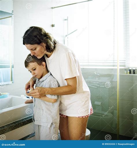 Mom Teaching Son Use Toothbrush in the Toilet Concept Stock Photo